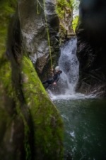 Canyoneer is Rappeling down Between Green Moss