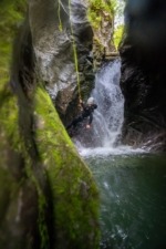 Canyoneer is Rappeling down Betwen Green Moss