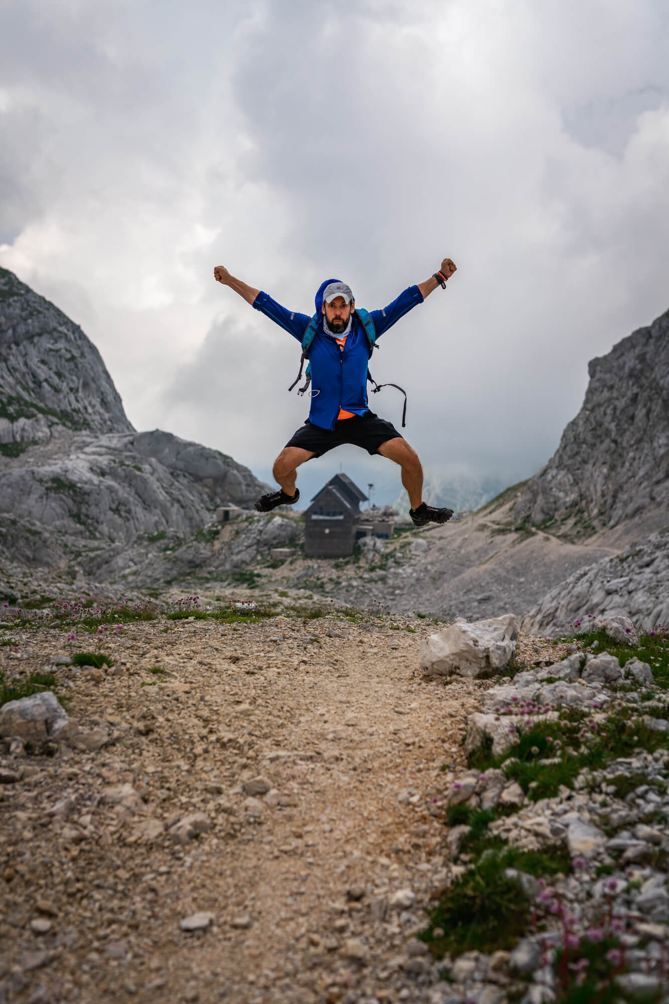 Hiker with Blue Jacket is Jumping above Dolic Hut, Julian Alps Hiker with Blue Jacket is Jumping above Dolic Hut, Julian Alps