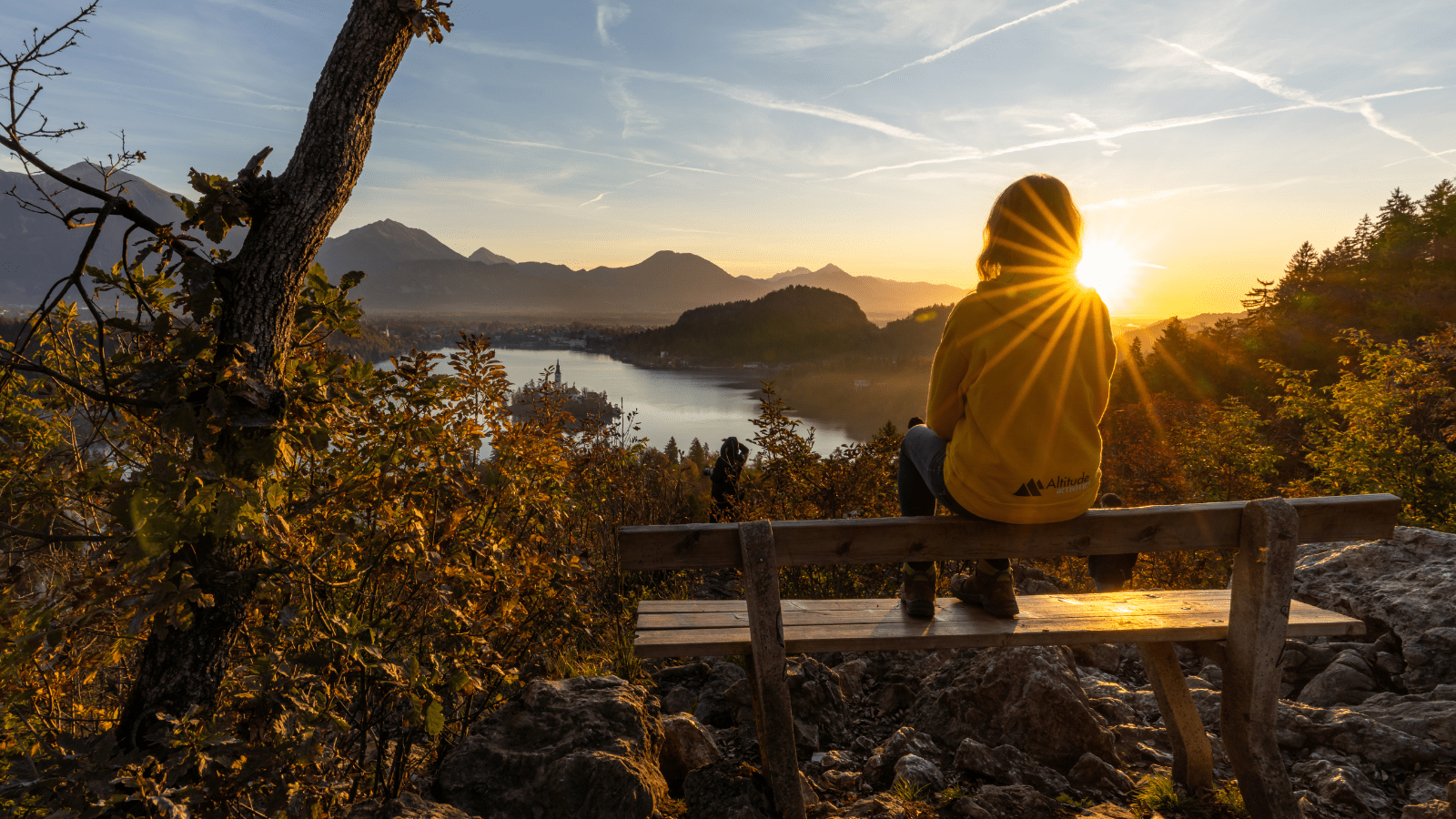 A girl peacefully enjoys the stunning autumn view over Lake Bled, surrounded by warm fall colors and the picturesque island in the distance.