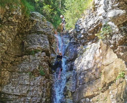 An adventurer enjoying natural tobogganing, leaping into the water, and rappelling down a waterslide in Triglav National Park's canyons