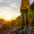 Female hiker stending on the rock admiring sunrise in the mountains