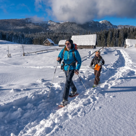 Slovenia winter activities: Two people snowshoeing on a snowy path