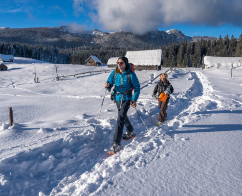 Slovenia winter activities: Two people snowshoeing on a snowy path