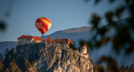Hot air balloon appears above a castle nested on rocky mountain