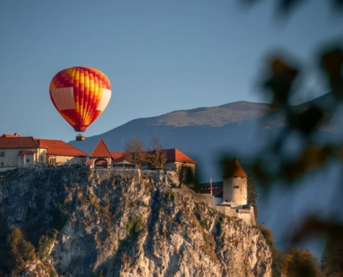 Hot air balloon appears above a castle nested on rocky mountain