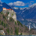 Blejski grad na skali nad jezerom z velikimi gorami v ozadju