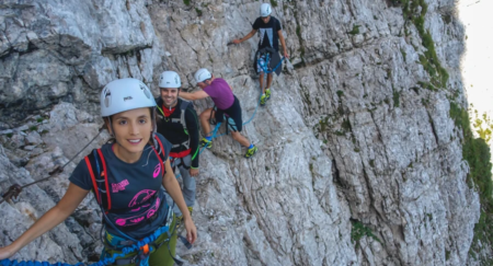 A group of friends is climbing rock formation on Via Ferrata