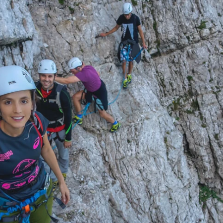 A group of friends is climbing rock formation on Via Ferrata