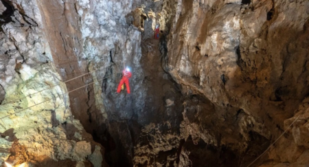 Extreme Caving Slovenia. A person is seen when sliding on rope in majestic Slovenian caves