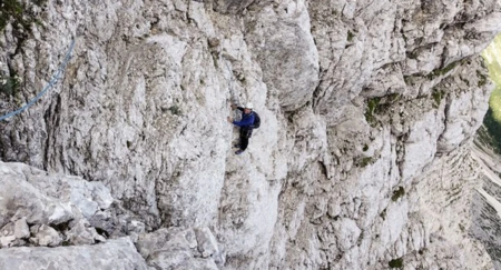 A person wearing white helmet is climbing a rock formation