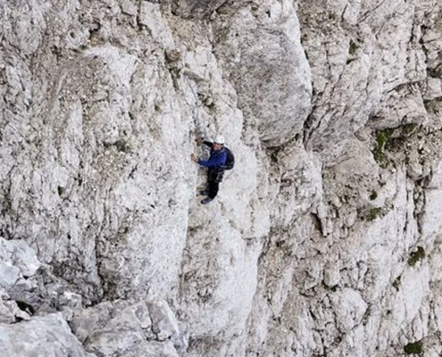 A person wearing white helmet is climbing a rock formation