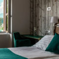 Udobna hotelska spalnica z zelenimi blazinami in dodatki s pogledom na jezero za oknom