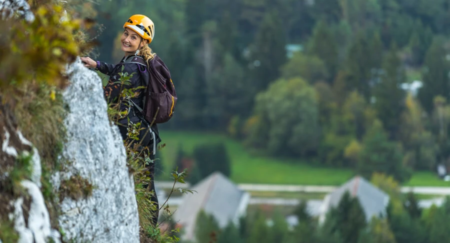 A person climbing on a rock formation is seen smiling to the camera