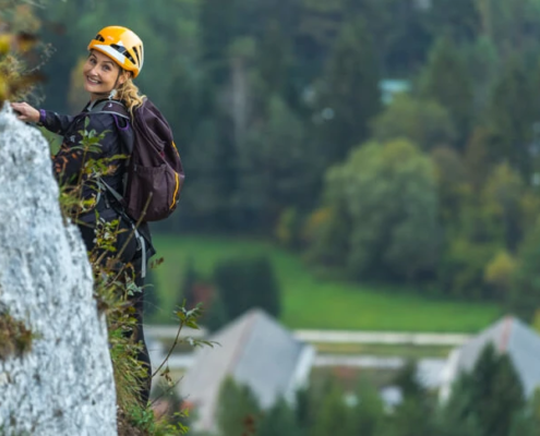 A person climbing on a rock formation is seen smiling to the camera