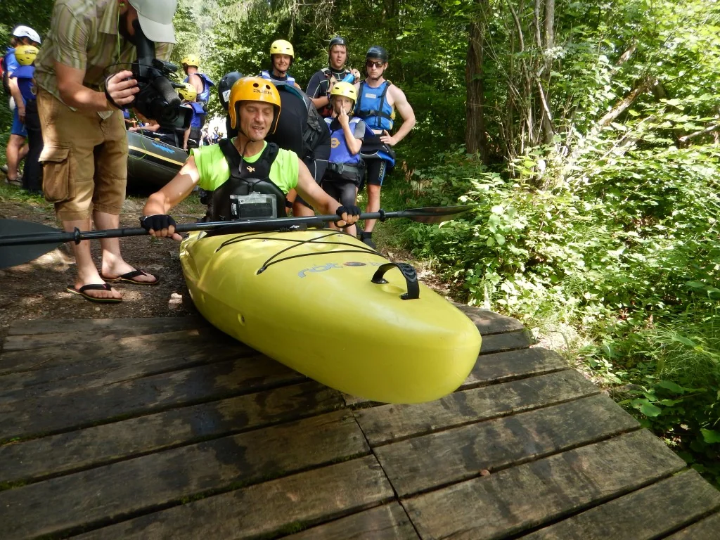 Kayaking Kayaking Slovenia: Smiling group with kayaks on a wooden dock in a forest, preparing for a water adventure.