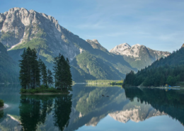 Bled Tours: Calm Lake Predil reflecting nearby alpine peaks and forested hills, with peaceful scenery capturing the beauty of northern Slovenia.