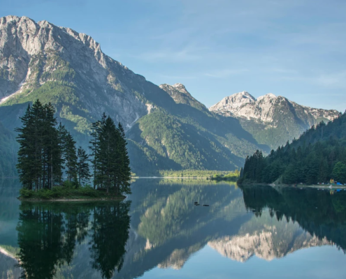 Bled Tours: Calm Lake Predil reflecting nearby alpine peaks and forested hills, with peaceful scenery capturing the beauty of northern Slovenia.