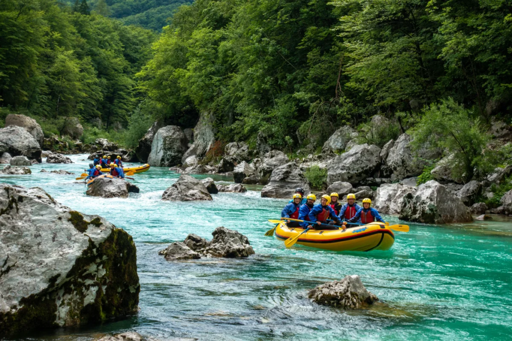 Rafting Rafting Slovenia: Group paddling a yellow raft through turquoise river rapids surrounded by rocky cliffs and forest.