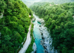 Bled Tours: An aerial view of the turquoise Soca River winding through dense green forest within the beautiful Triglav National Park in Slovenia.