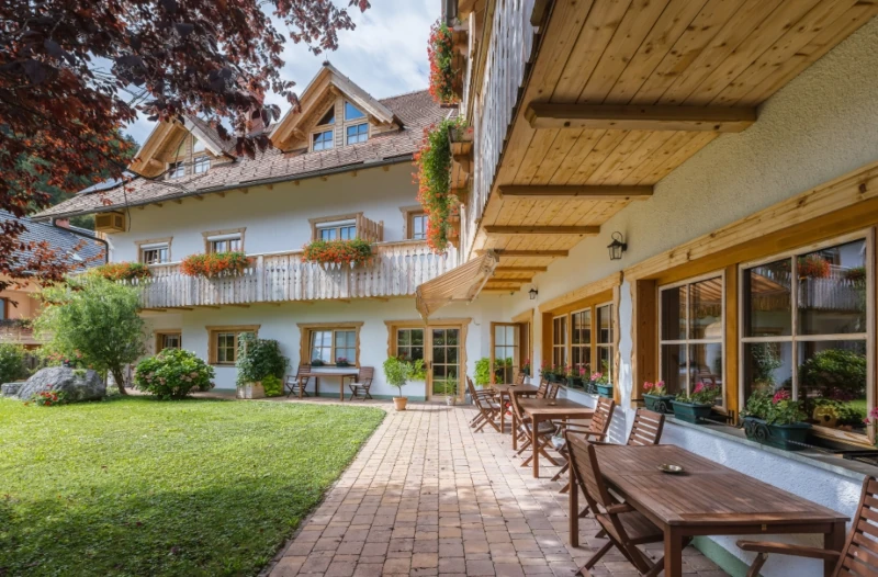 Charming hotel with garden terrace and rustic wooden balcony.