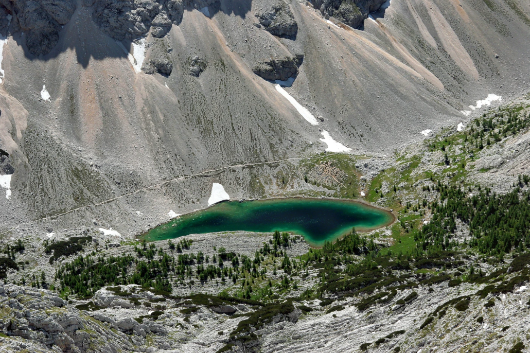 Turquoise alpine lake nestled below rocky grey slopes in the Seven Lakes Valley, Slovenia